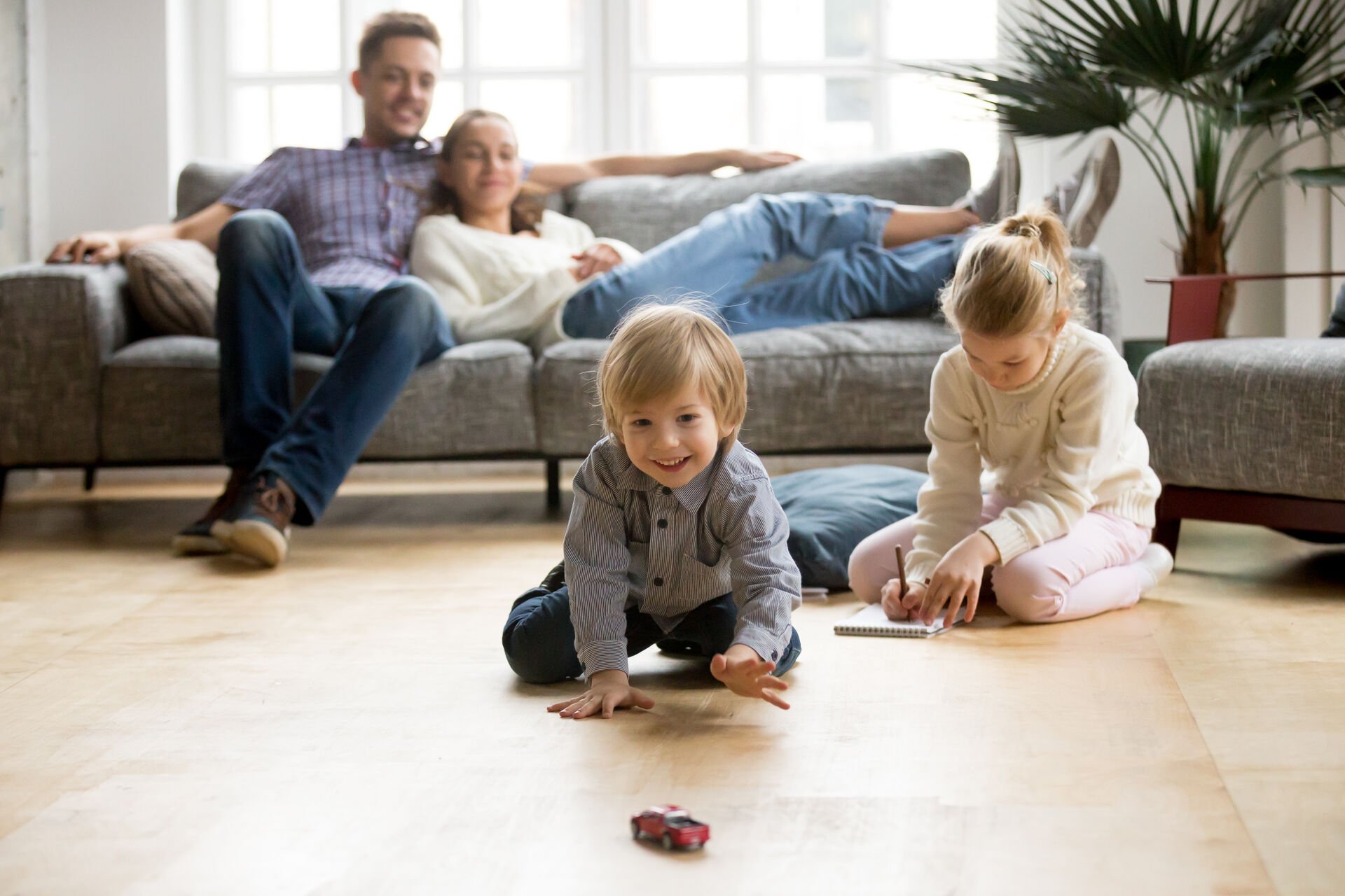 kids playing on floor and parents on couch