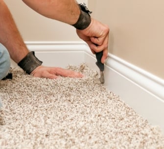 Person installing carpet along baseboards