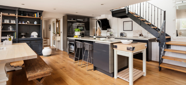 Industrial style kitchen with dark cabinets and light wood floors