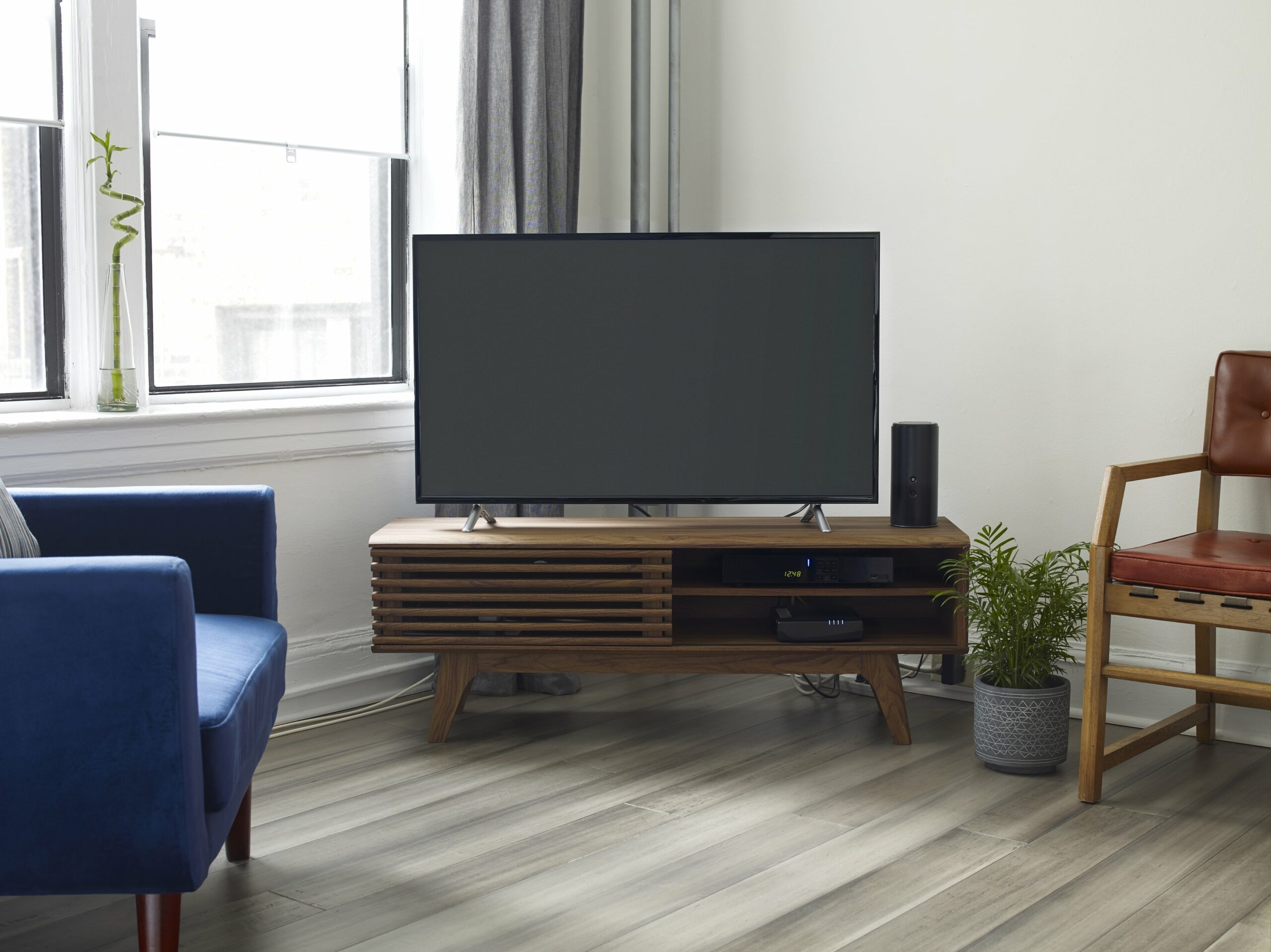 Room with vinyl floors, blue chair and tv on stand