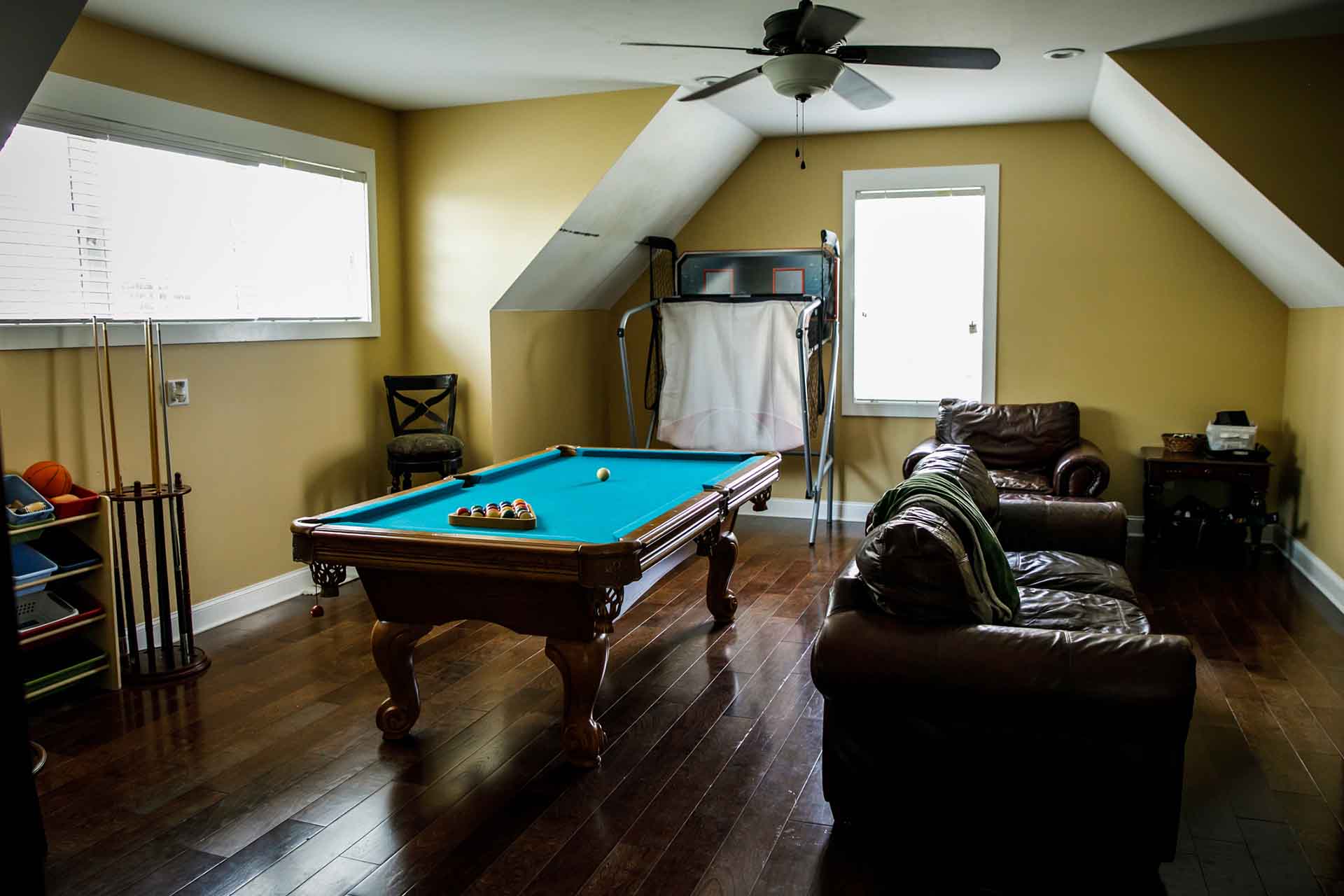 man cave with wood floors, pool table and basketball game