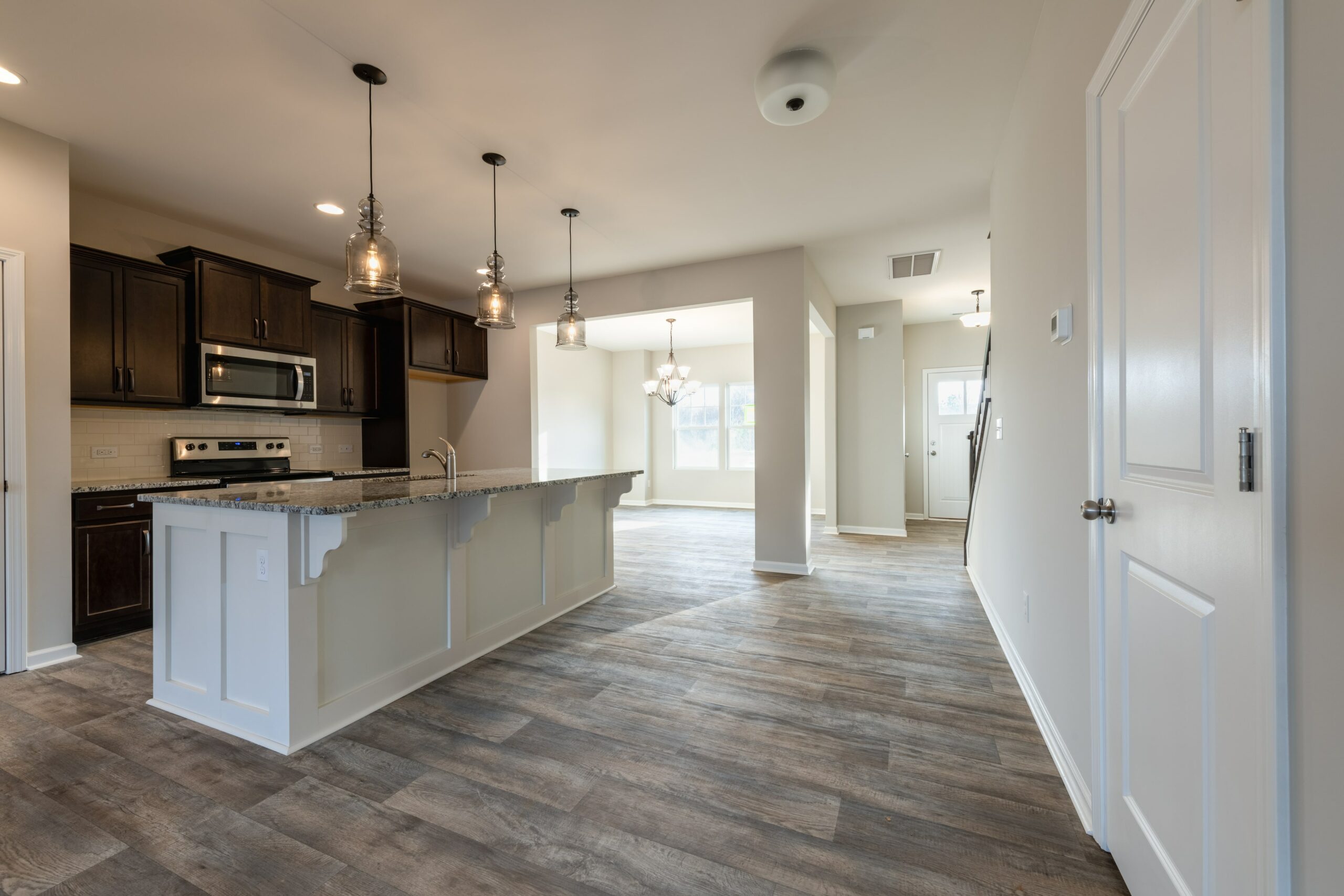 Kitchen with wood floors, white cabinet island and dark cabinets