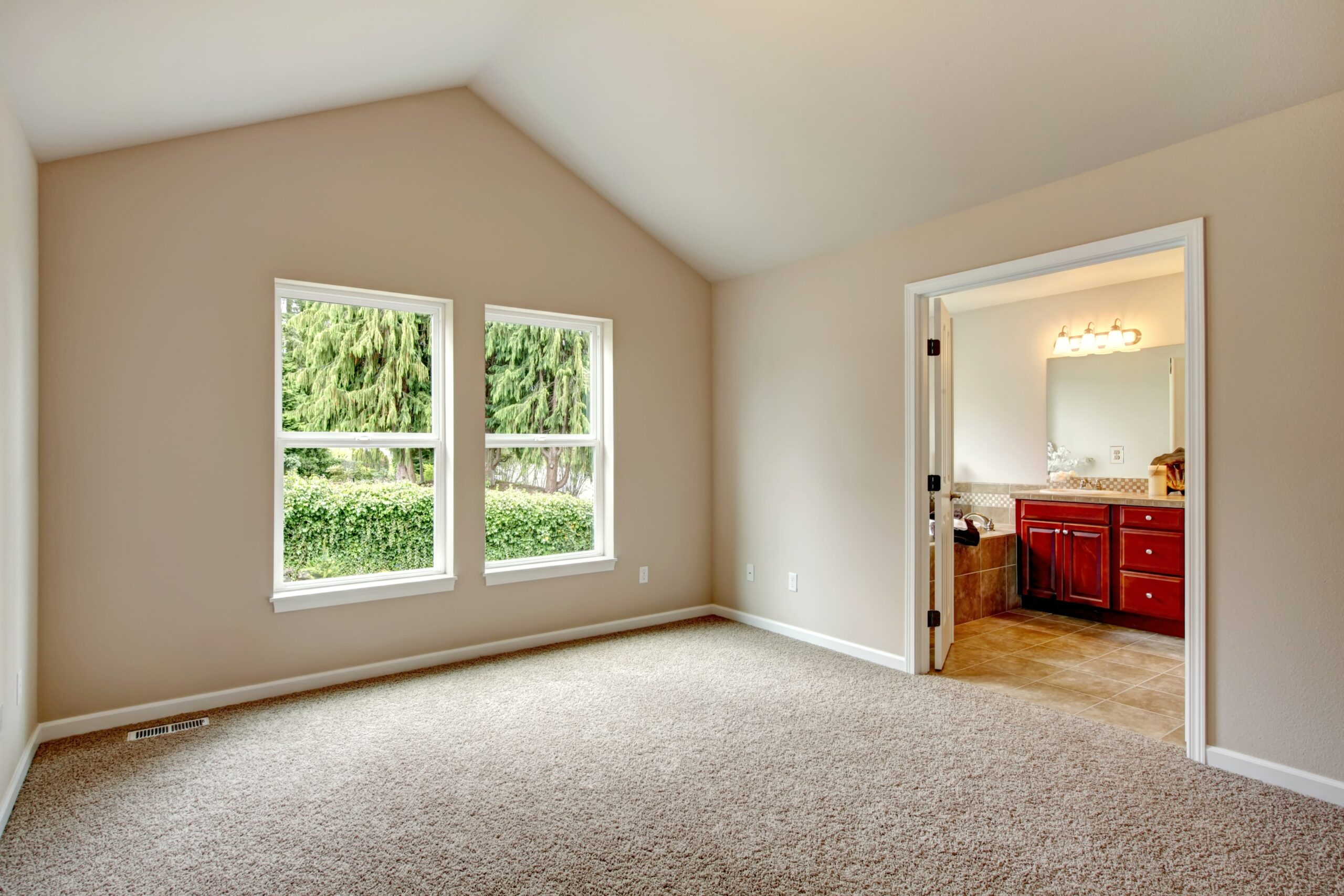 Bedroom with carpet leading into bathroom with tile floors