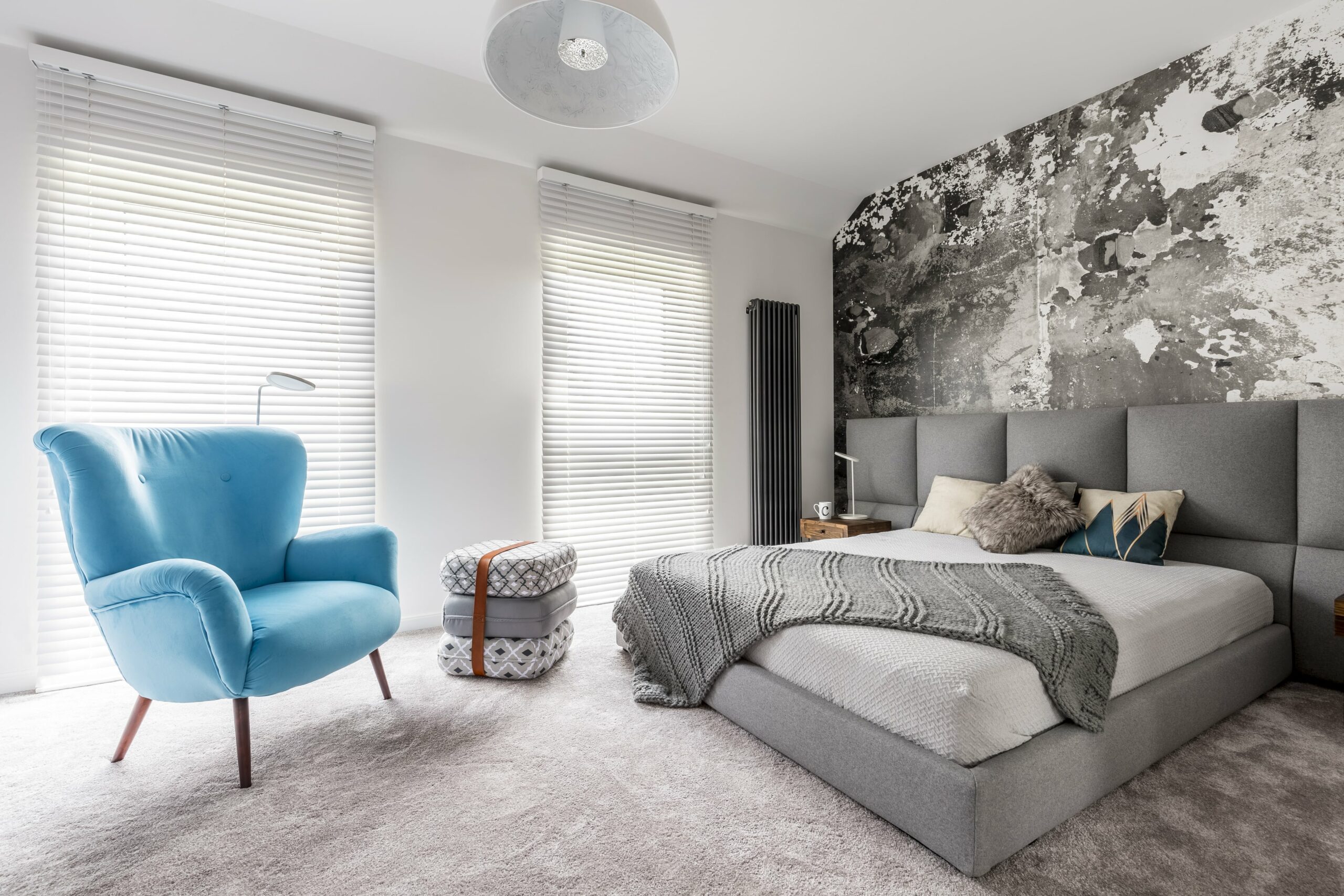 Room with carpet, blue chair and grey bed