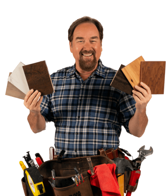 Richard Karn holding flooring samples and wearing tool belt